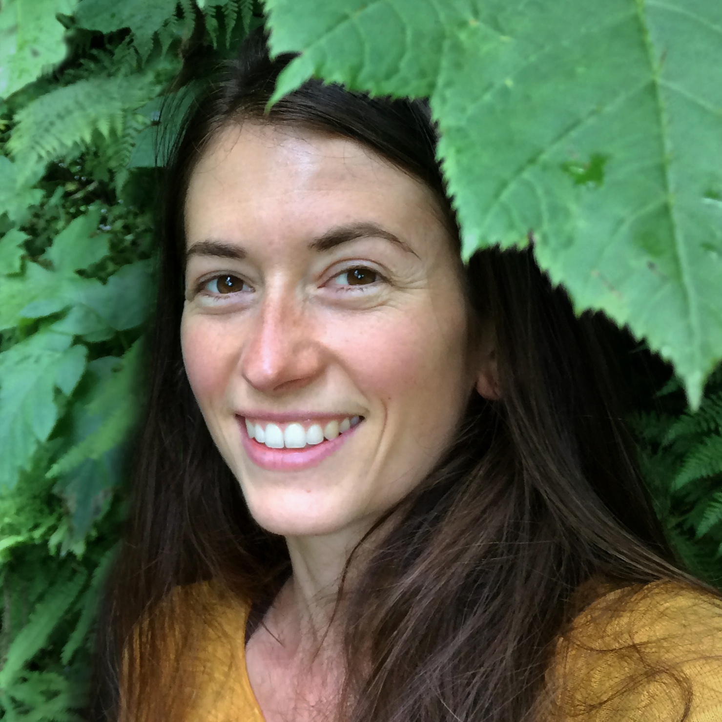 photo of a woman's face, framed by green leaves