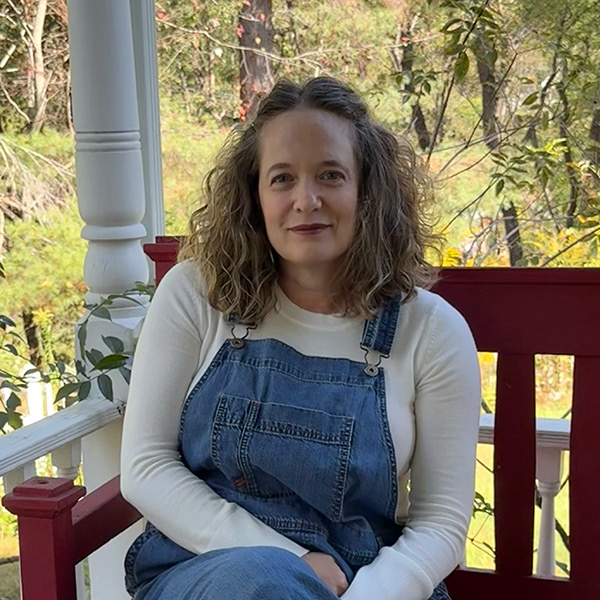 photo of a woman in overalls sitting outside on a bench
