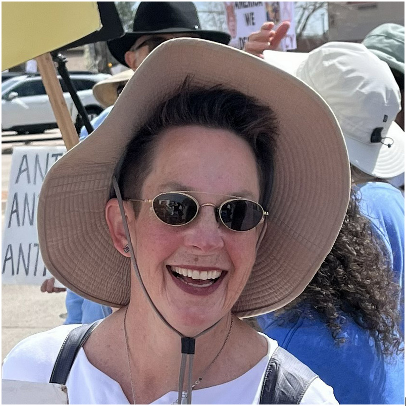 Photo of a smiling woman's face, wearing a hat and sunglasses
